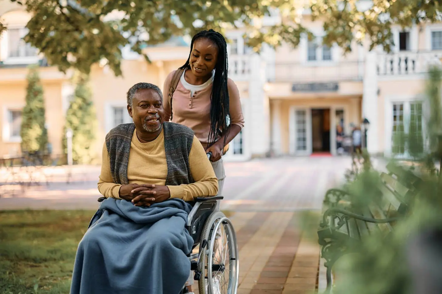 Happy woman pushing senior person in wheelchair
